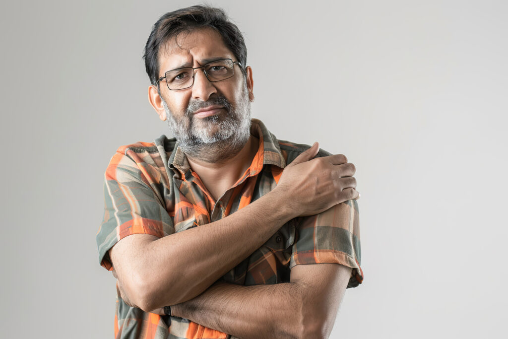 Middle aged Indian man in pain with frozen shoulder symptoms