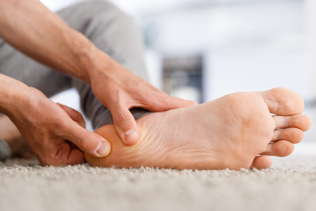  male hands rub the underside of a mans heel.