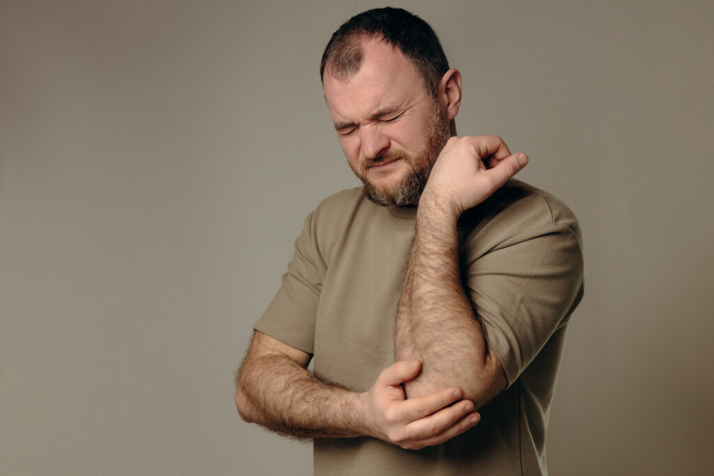 Man experiences elbow pain due to joint problems, arthritis, bursitis or epicondylitis tennis elbow. diagnosis treatment, physical therapy or use of painkillers. diseases musculoskeletal system.