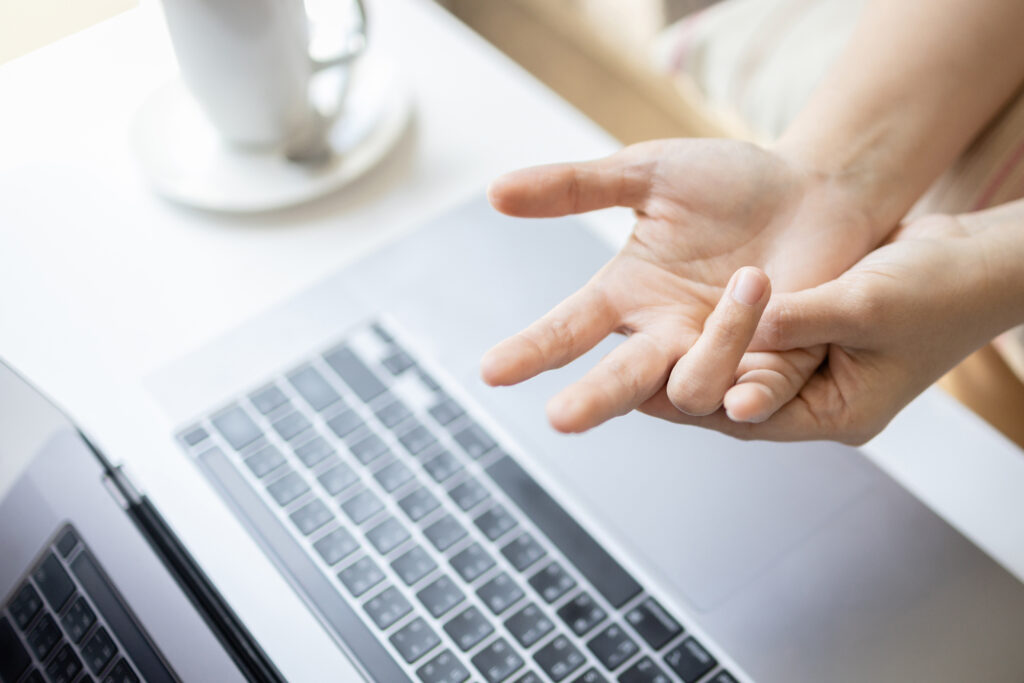Close-up,Hand of asian woman massaging her palm,suffering from trigger finger disease,tendon problem,pain in hand and fingers,trigger finger from typing on keyboard for long period of time.