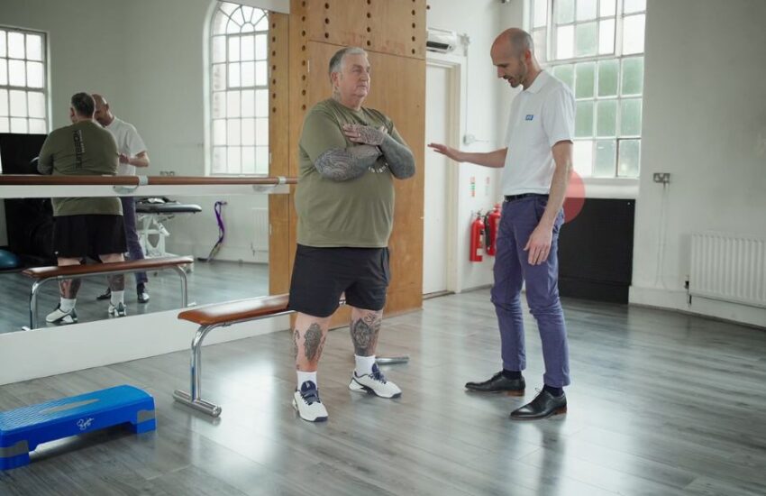 Physio helps patient to exercise in gym