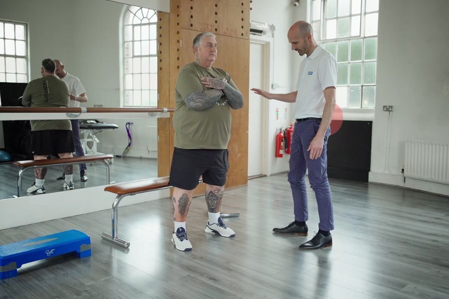 Physio helps patient to exercise in gym