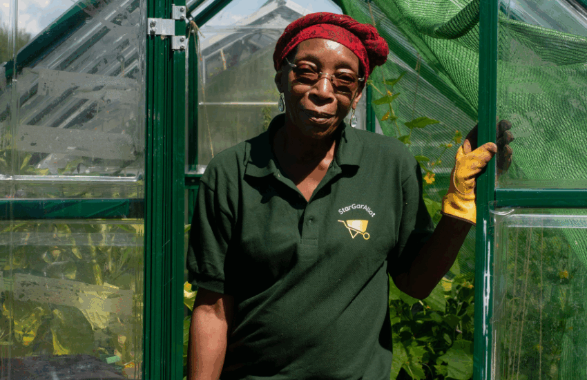 Woman standing in door of greenhouse looking at camera